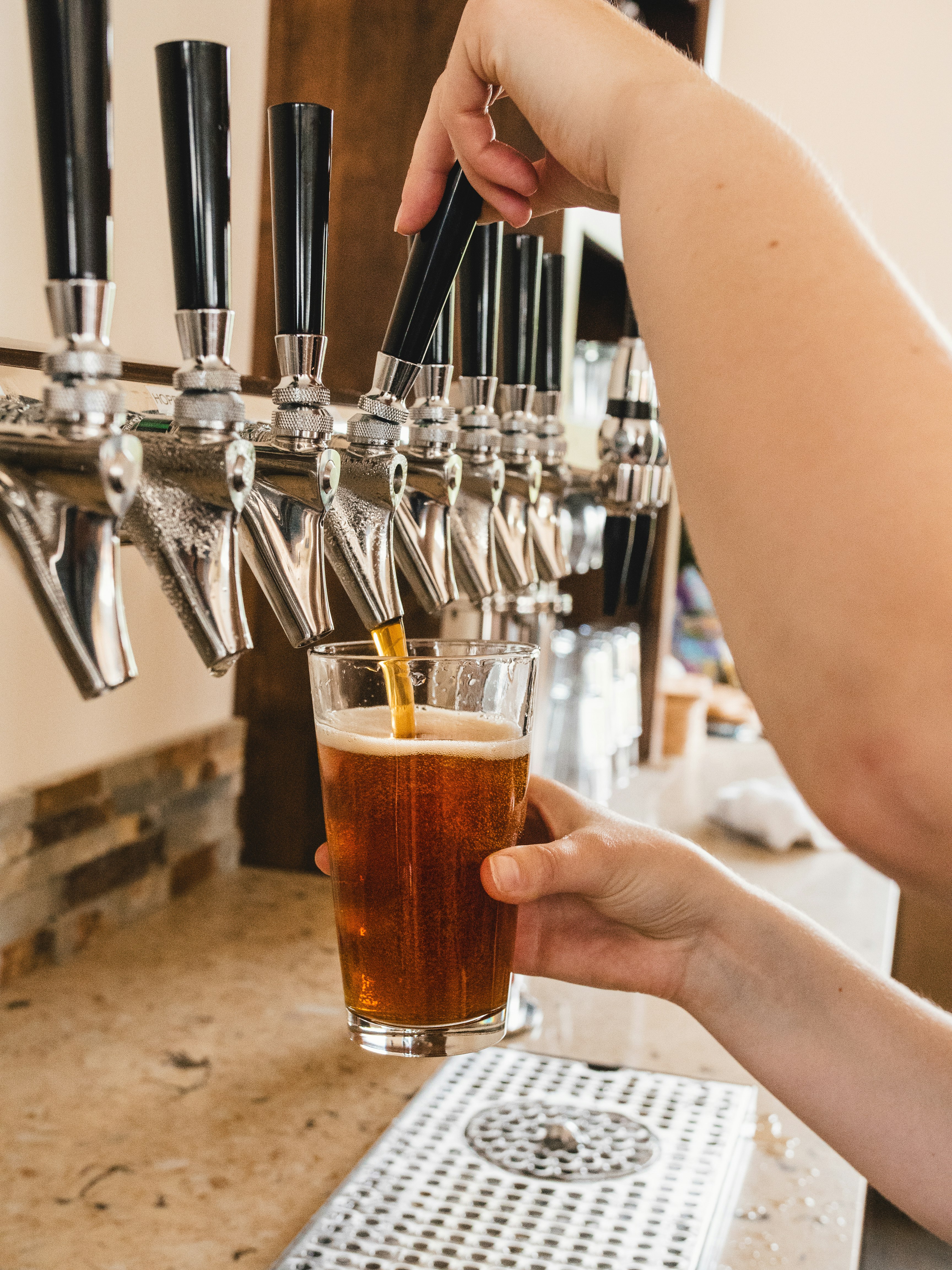 person holding clear drinking glass with brown liquid